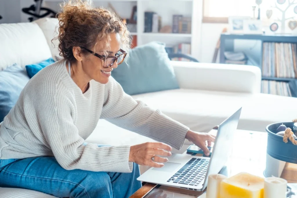 Woman sitting on couch and using laptop to make an NDIS referral